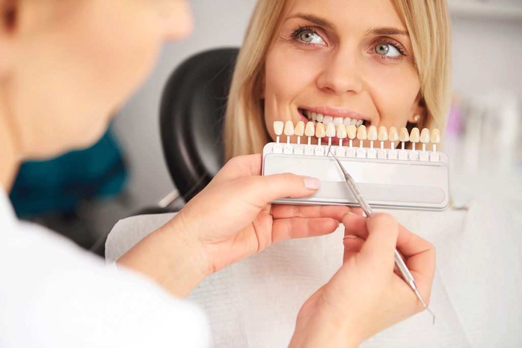 dental professional uses a tooth color matching device to explain the teeth whitening cosmetic dentistry procedure.