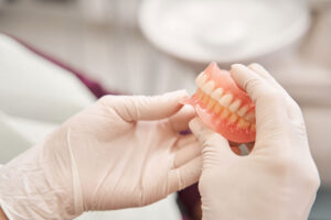 close up of prosthodontic professional inspecting finished pair of full dentures
