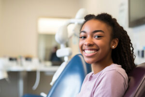 smiling young girl seated in dental office wondering what are 5 questions to ask your new dentist?