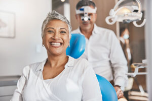 smiling female patient in dental chair about to receive dental care after learning how do most patients select a new dentist